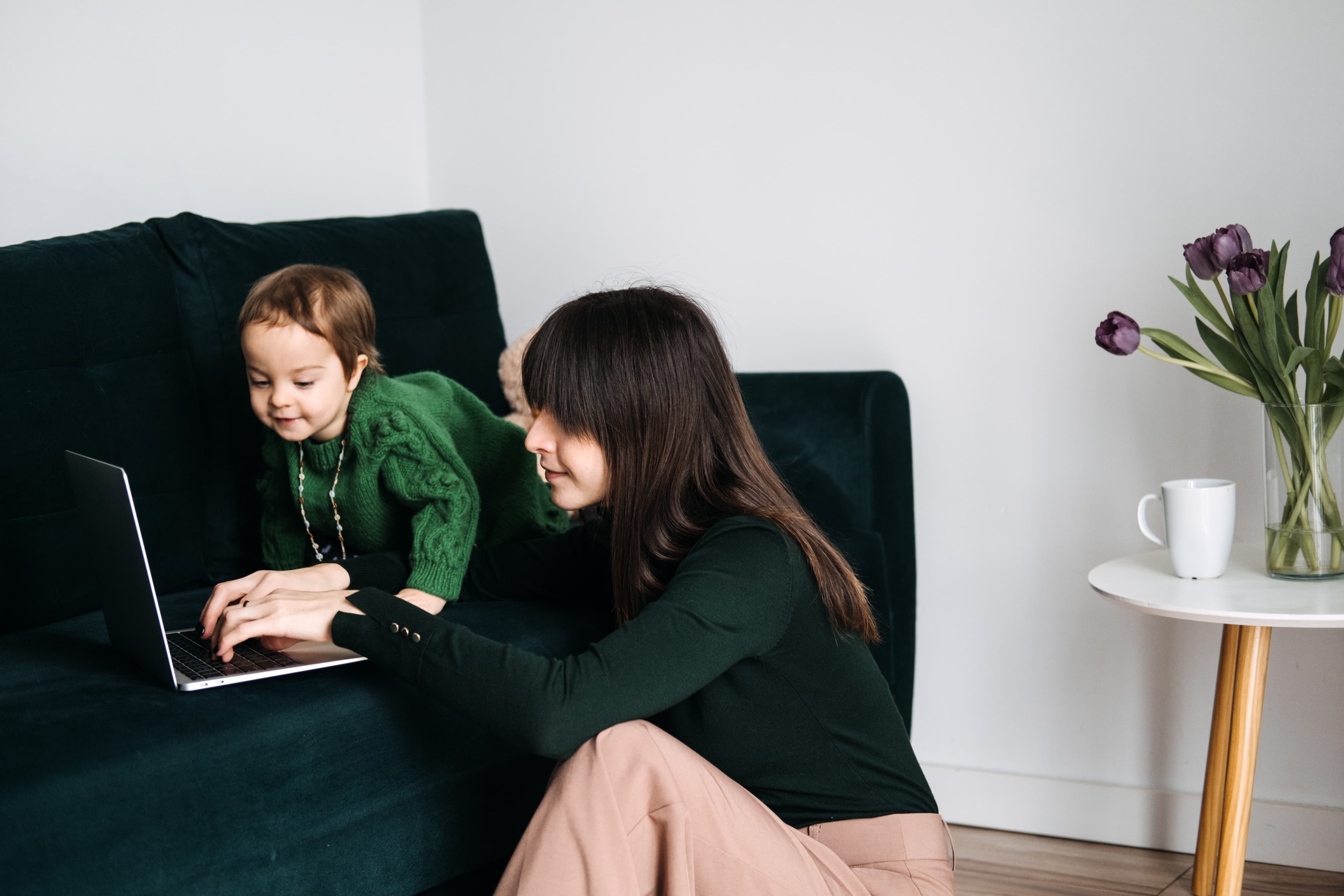Mutter arbeitet am Laptop mit Kind — Beruf und Familie vereinen