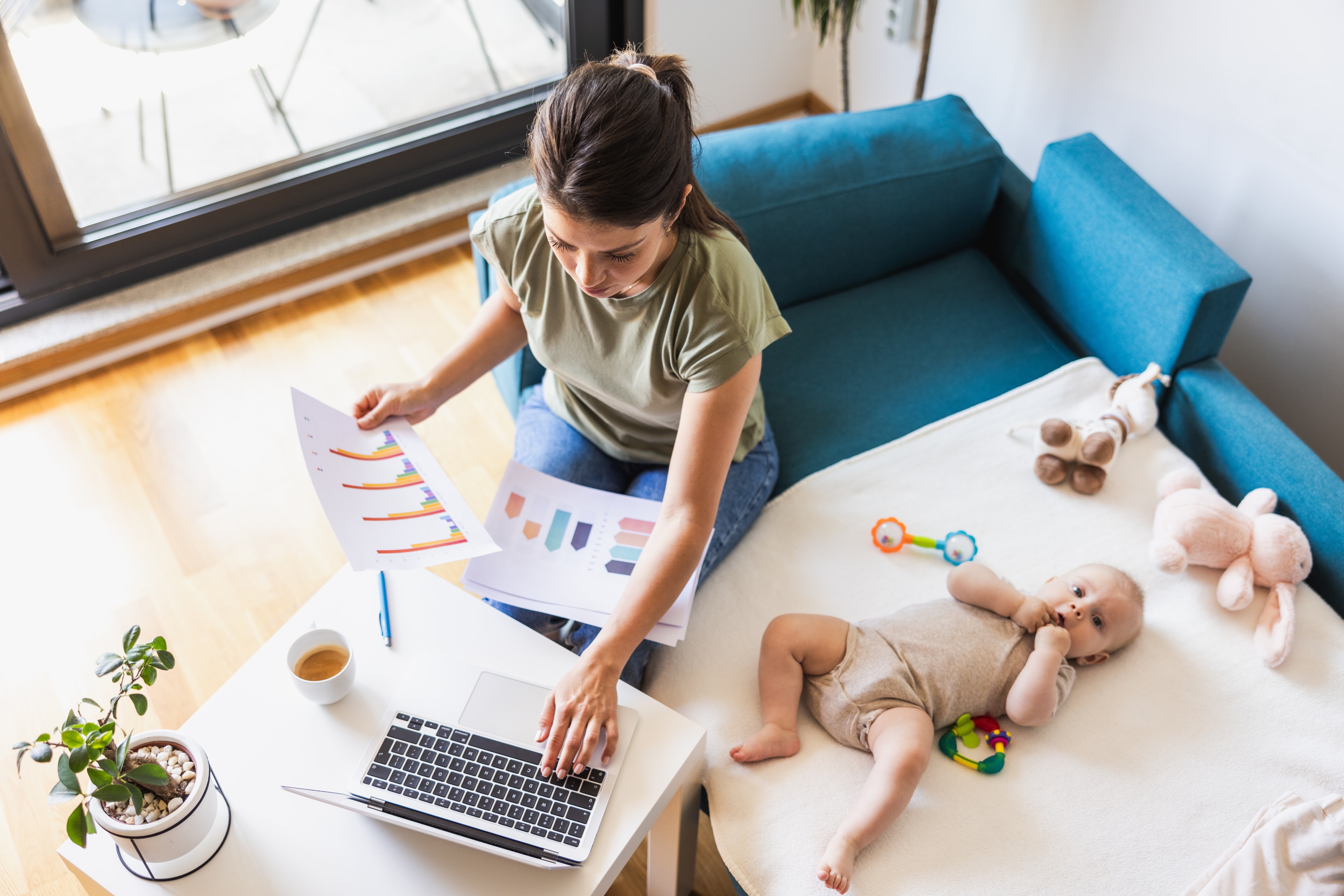 Mutter arbeitet am Laptop neben ihrem Baby — Beruf und Familie vereinen